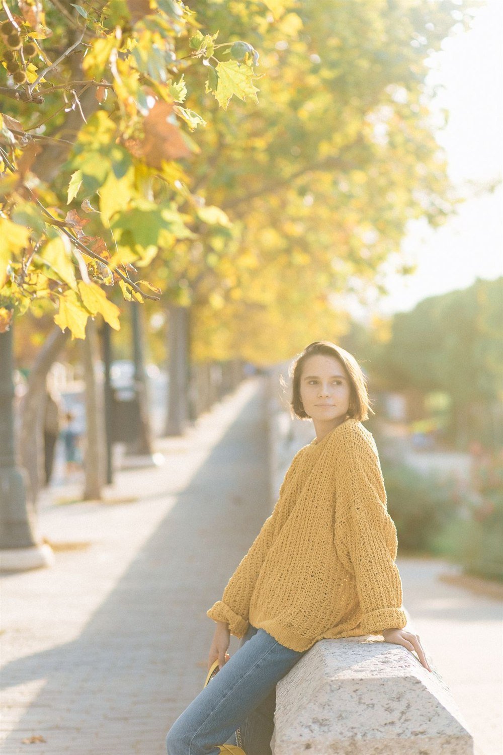 A model wearing a soft knit on a tree-lined street