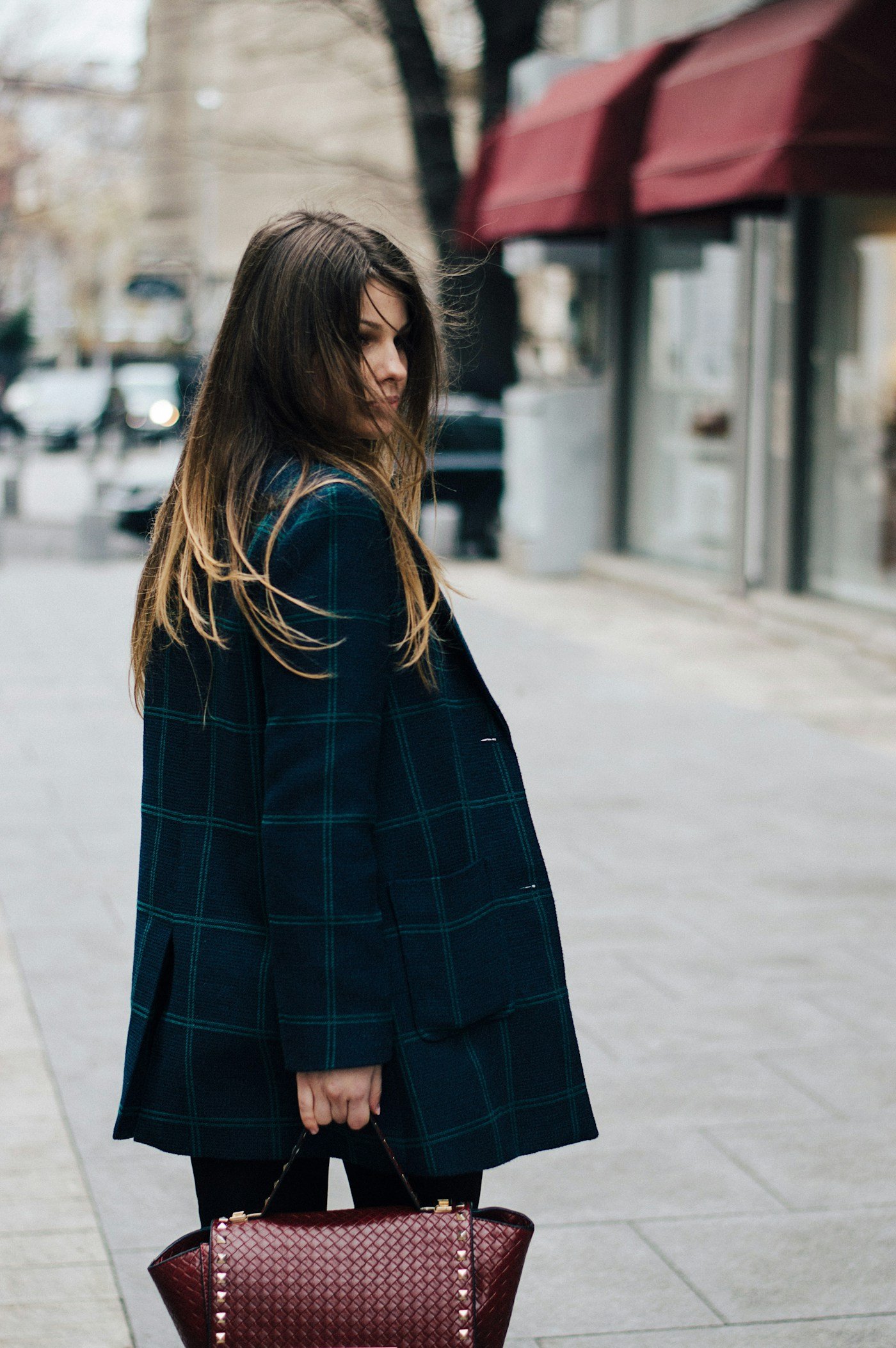 A black coat and leather bag on a city street